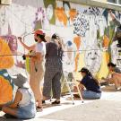 Students paint a mural on a school building