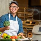 A male student poses with fruits and veggies in the research kitchen