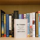 Wooden bookshelf with assorted books, 'On Tyranny' displayed front-facing center
