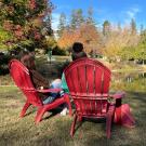 People sit in Adirondack chaiurs along Lake Spafford