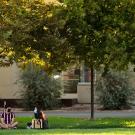 Students sit and chat outside the Segundo Dining Commons as another student rides past on a bicycle.