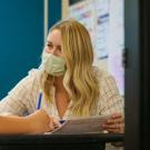 Woman sits at desk with young student.