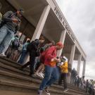 Students walk down the stairs outside Rock Hall. A cloudy sky is seen in the background.