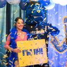 Student poses with Gunrock while holding gold sign reading "I'm in" as confetti falls