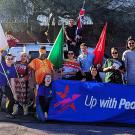 Marchers with flags and a banner smile and shout on the street - Aggies Abroad UC Davis