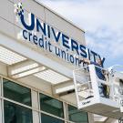 Worker installs University Credit Union Center signage.