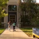 Two women walk toward Walker Hall main entrance.