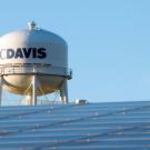 Campus water tower seen with solar panels in the foreground.