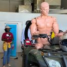 Tour group views all-terrain vehicle with mannequin in the driver's seat, for safety research