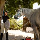 A student leads a horse at a barn. 