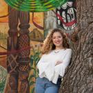 A student poses beside a mural. 