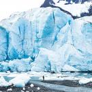 A man stands on the water’s edge at the foot of the massive vertical face of the Spencer Glacier in Alaska. (Getty Images)