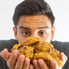 Wide-eyed young man gazes at pile of homemade cookies held in his hands.