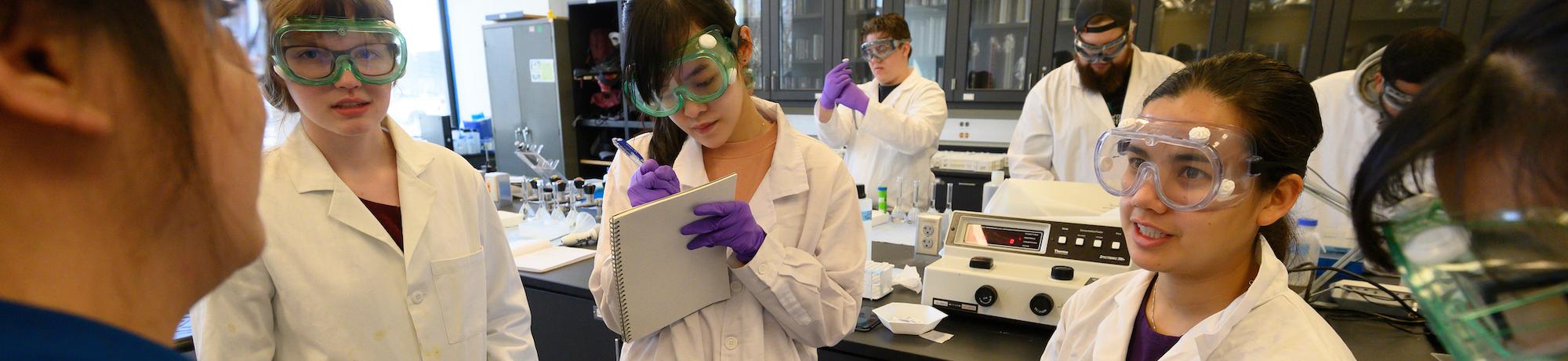 Students in goggles confer in a lab at UC Davis. 