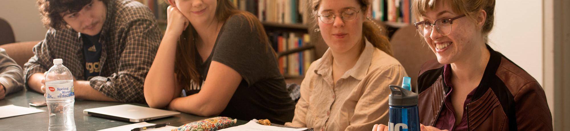 Students gather around a small table in a lively discussion with their professor