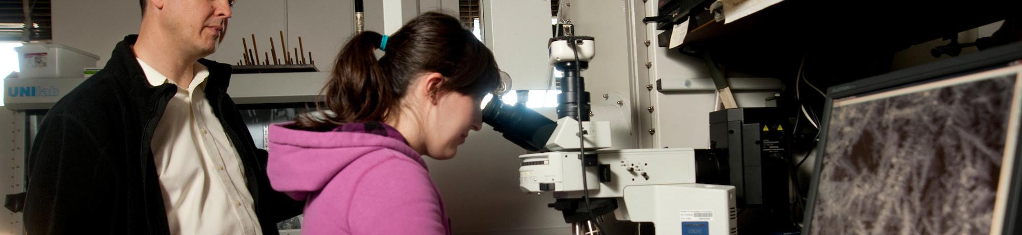 A student and her professor examine a slide specimen