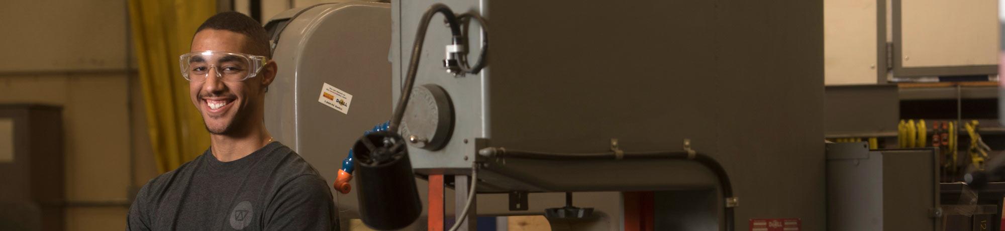 A male student poses with a machine press