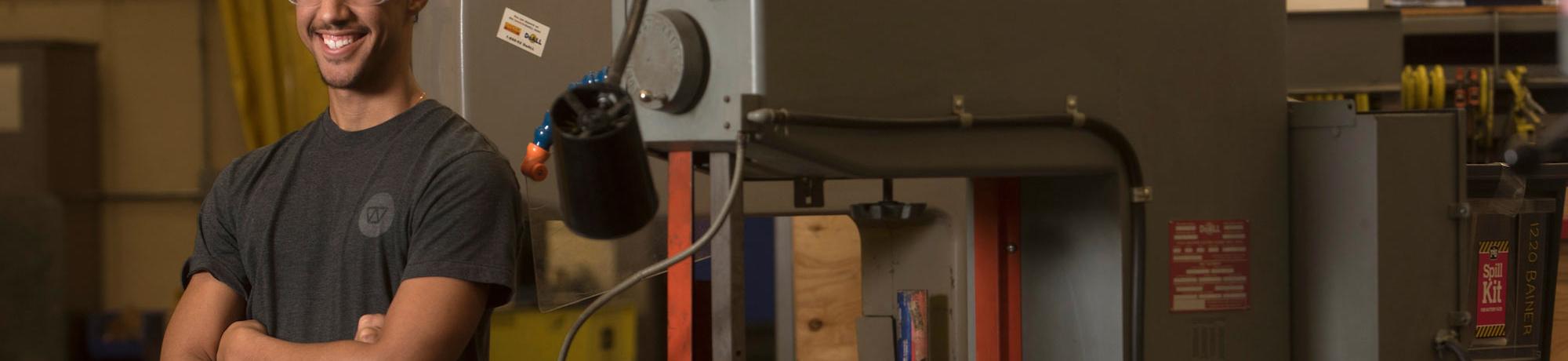 A male student poses with a machine press