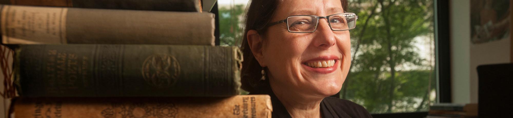 A professor of 18th century literature poses next to her book collection