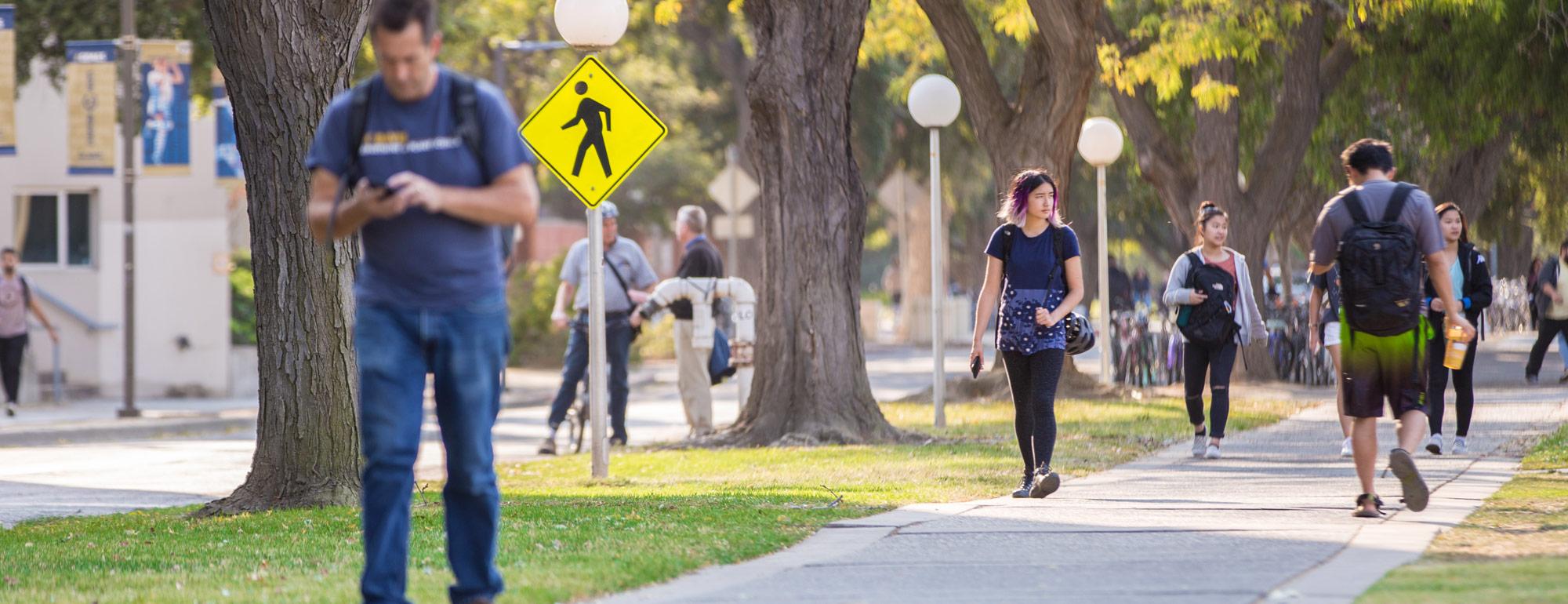 students walking down the sidewalk next to the quad