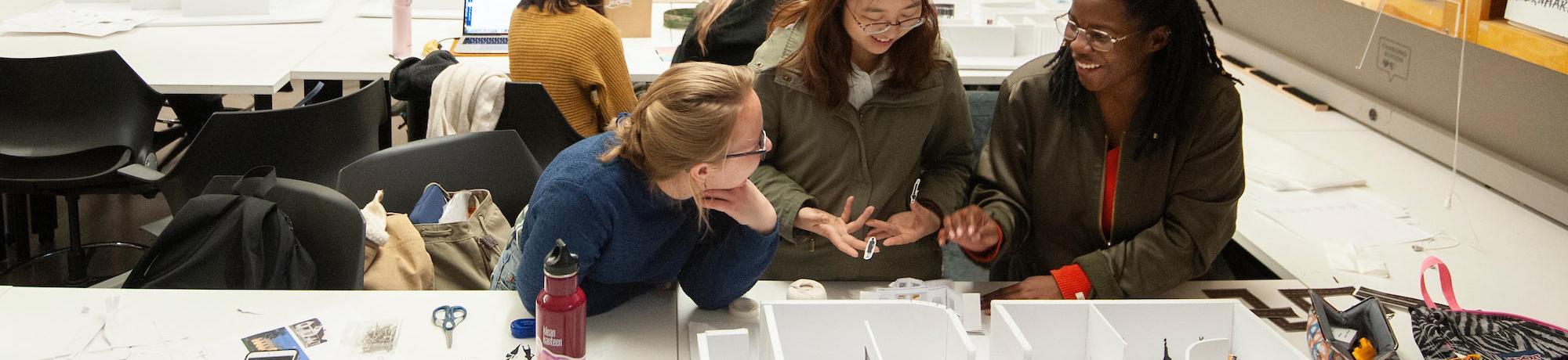 Three female students discussing a design model