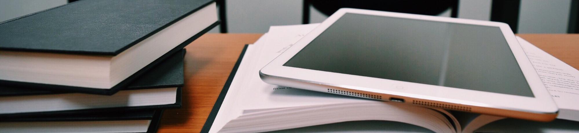 white ipad on top of open textbook