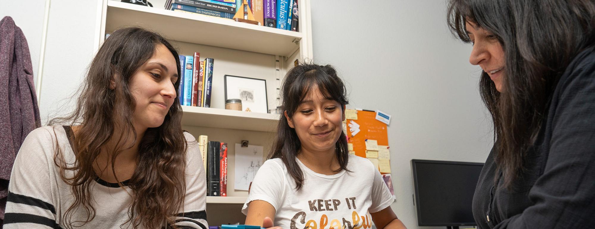 two students and a professor working together in office