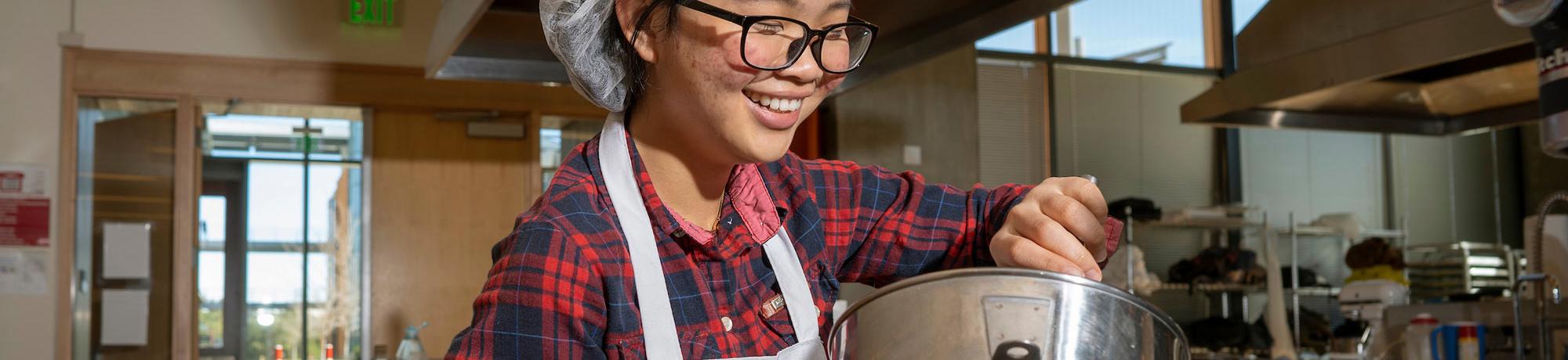 A female student mixes a food preparation in the UC Davis food lab