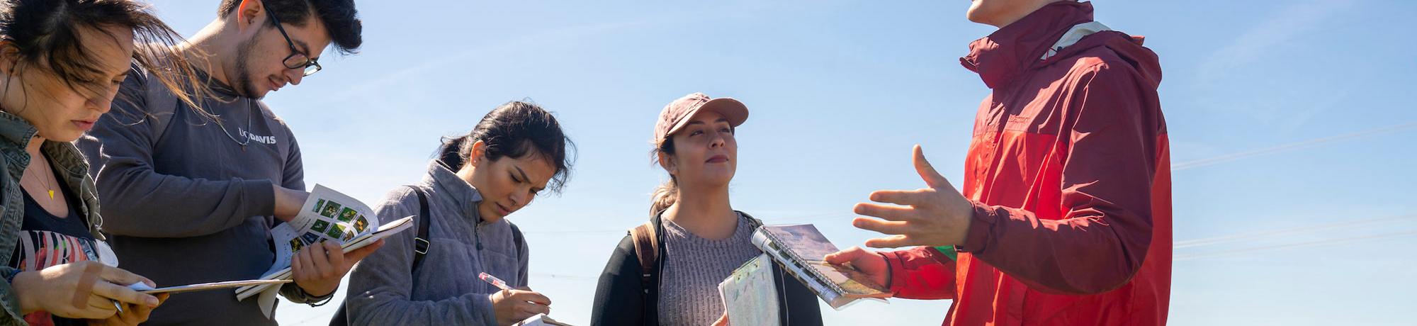 A student teacher lectures his class in the field