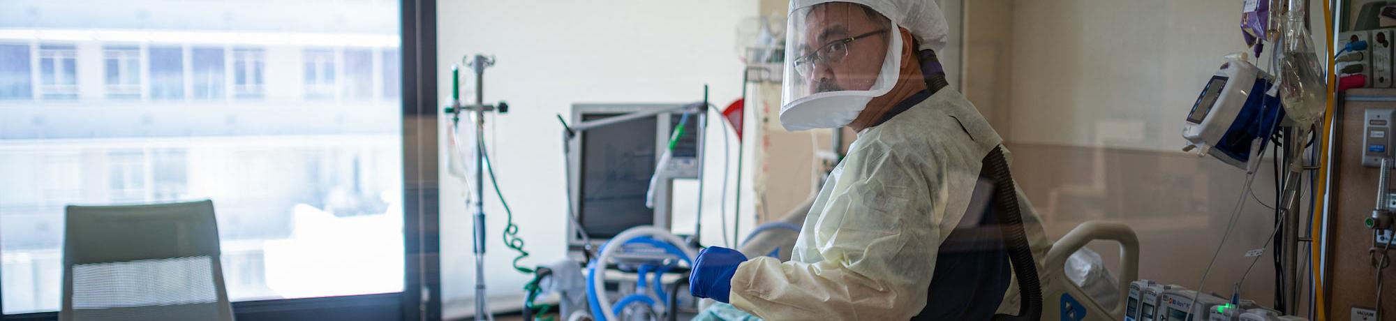 A nurse in full hazmat attends to a patient