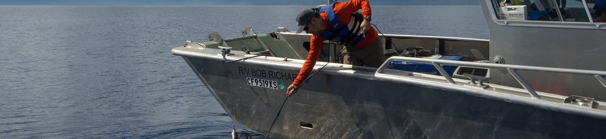 A researcher reaches into the waters of Lake Tahoe to secure a water sample