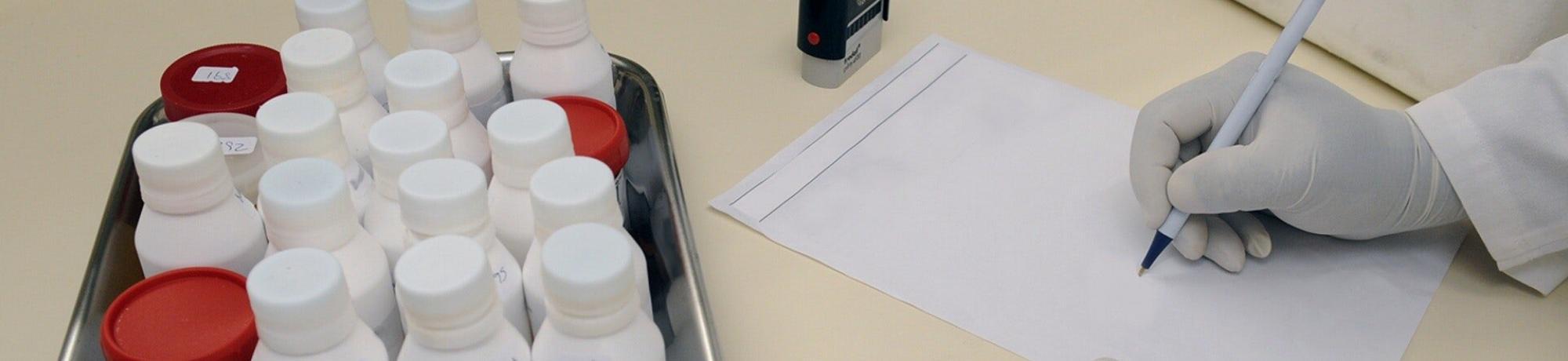 white bottles in a box next to person taking notes