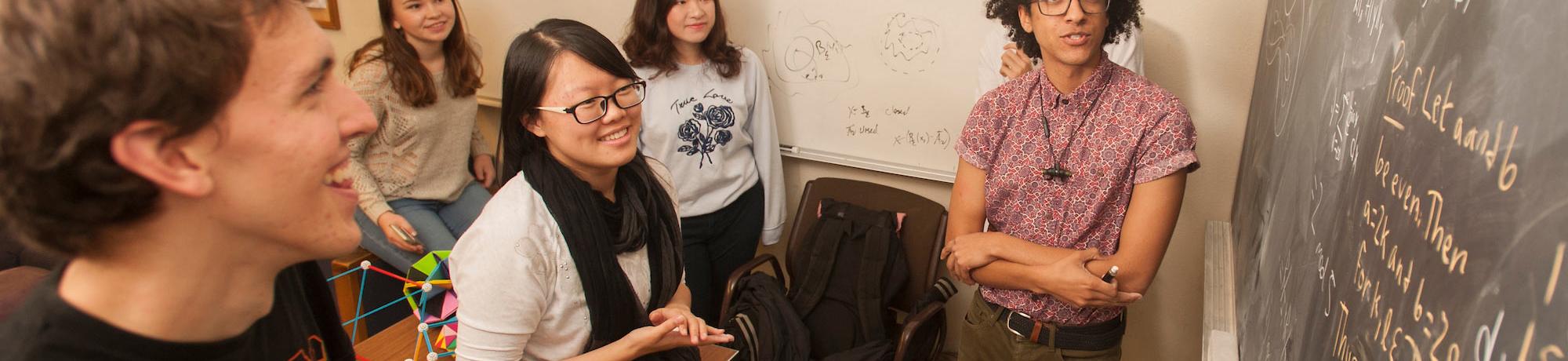 A group of math students considering a complex problem on a blackboard