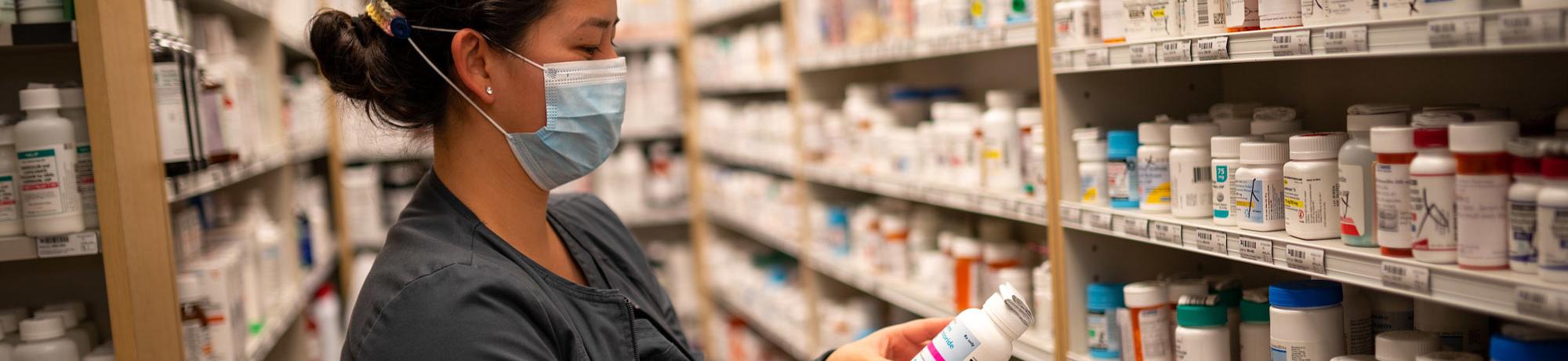 A woman examines a shelf of prescription medicine