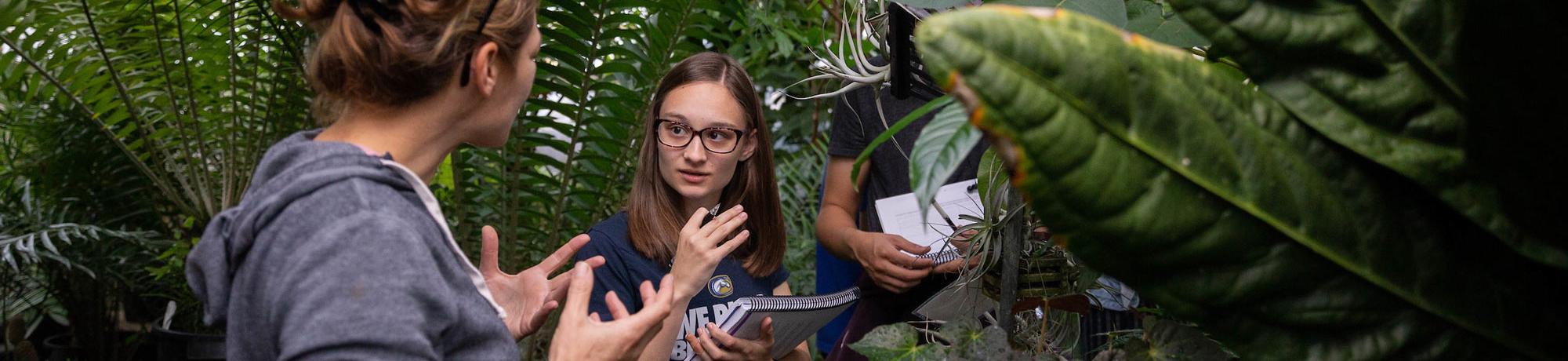 A student discusses a plant specimen with her professor in one of UC Davis's several green houses