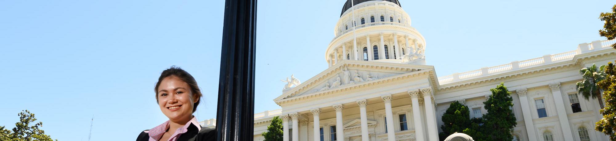 A female student poses with the California State Capitol building in the background