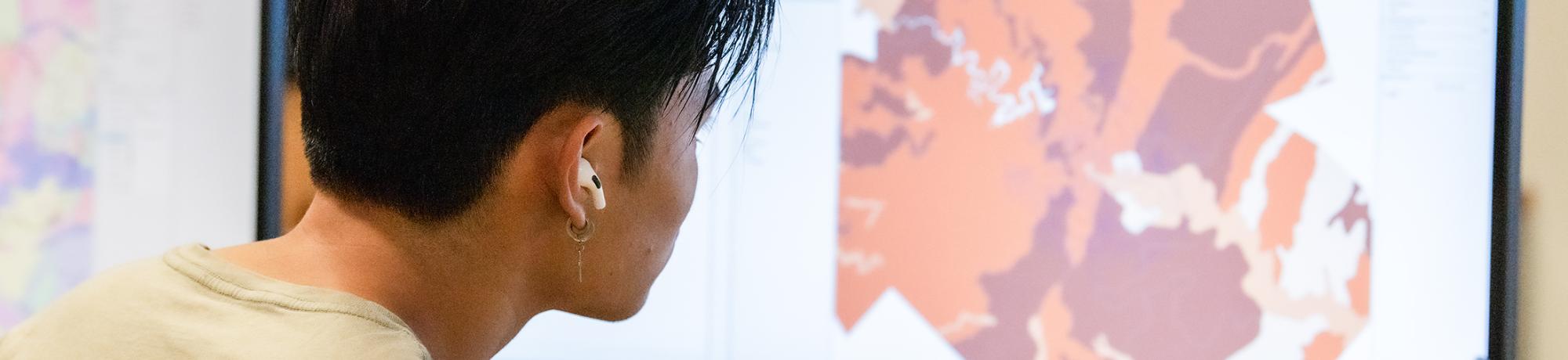 A student examines a map, in shades of orange and red, on a computer screen.