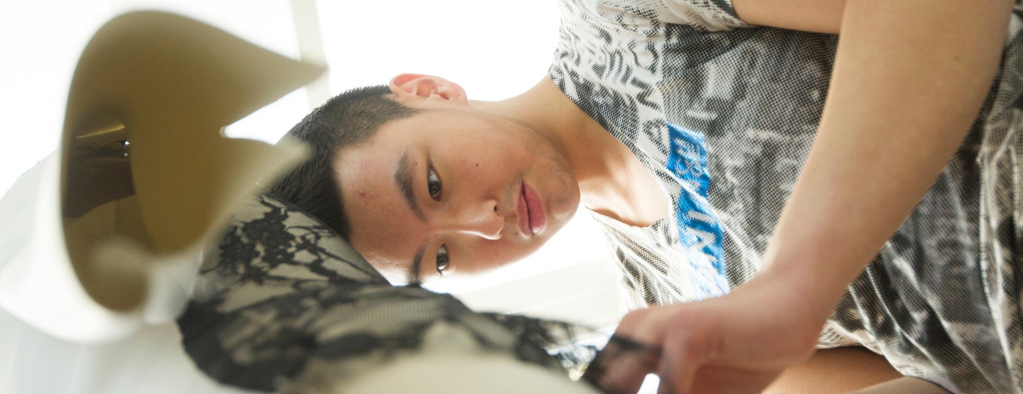 A male student makes an alteration to a dress he has created