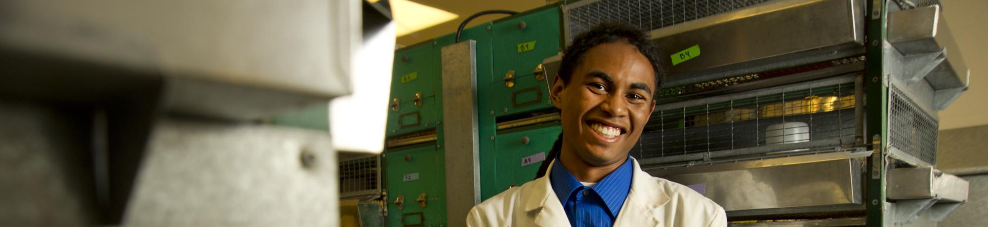 student wearing lab coat smiles in lab