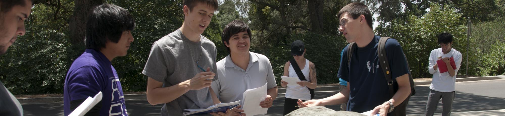 uc davis students talk and hold papers in a group