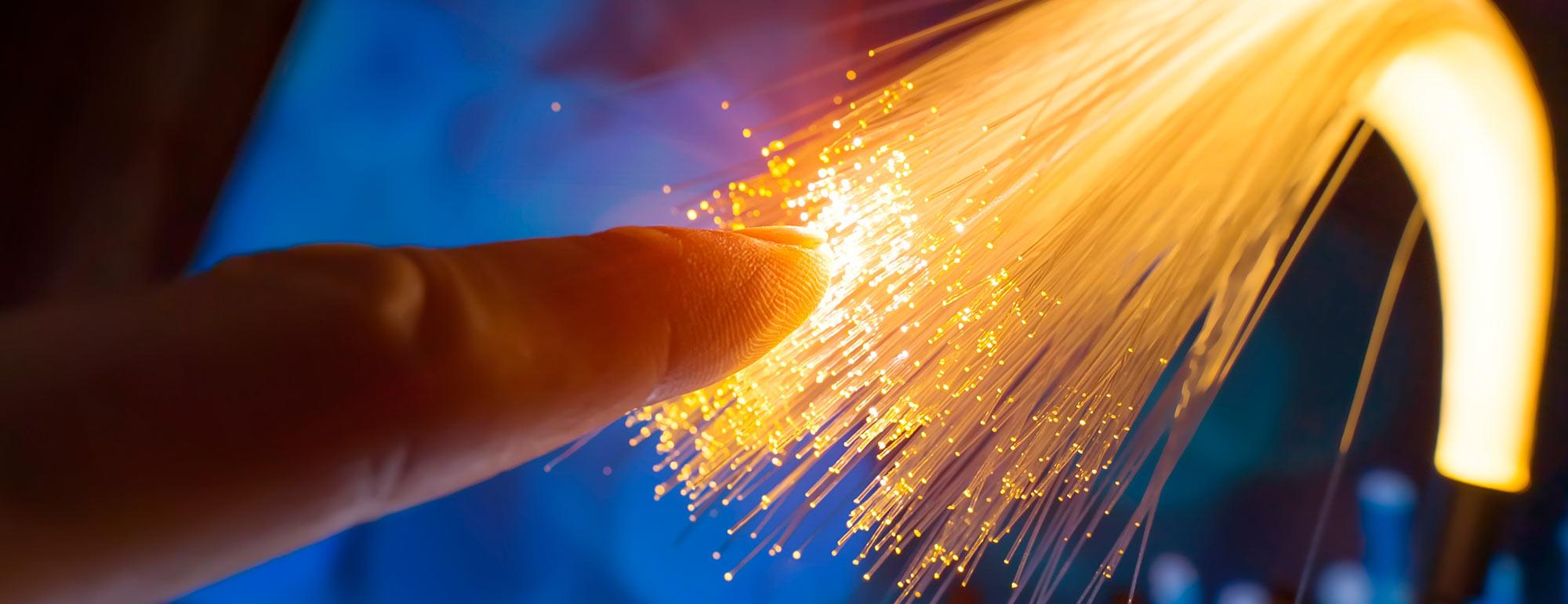 A person's finger touching the end of a bundle of illuminated fiber optic cables