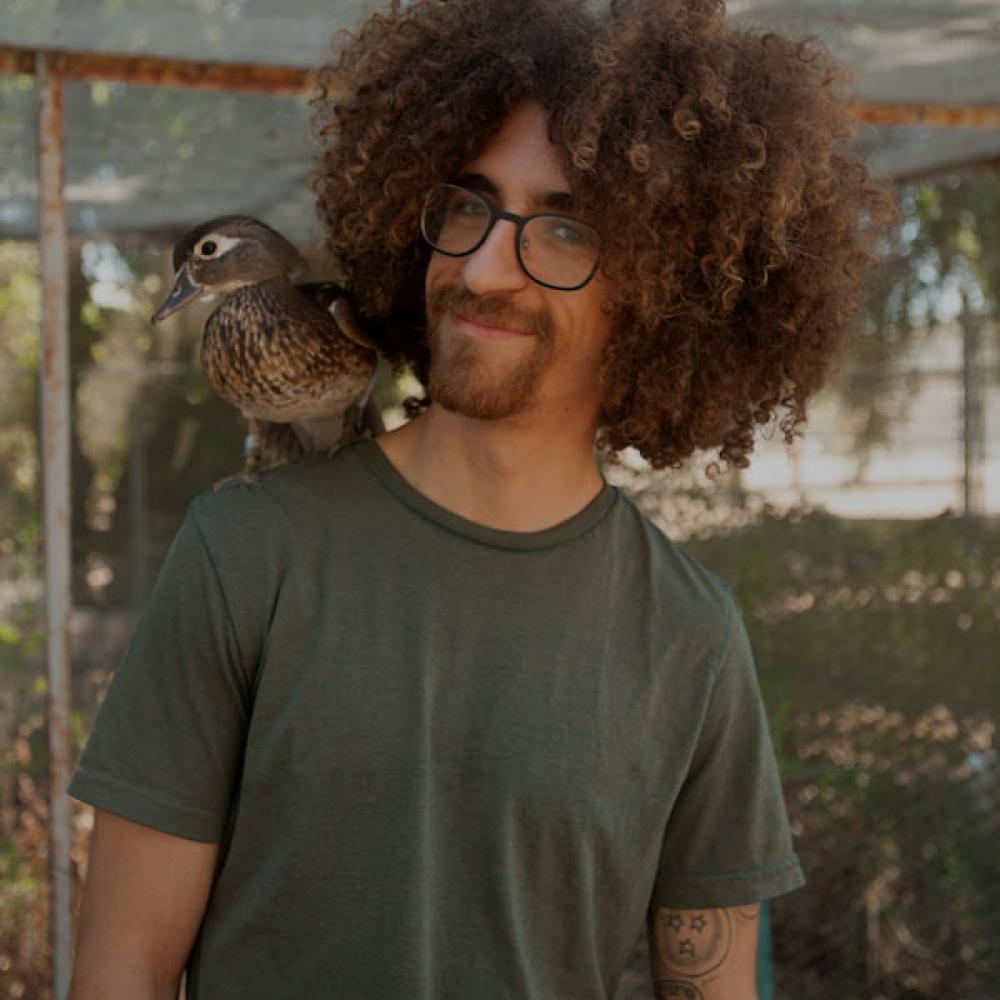 A male student stands with a duck on his shoulder