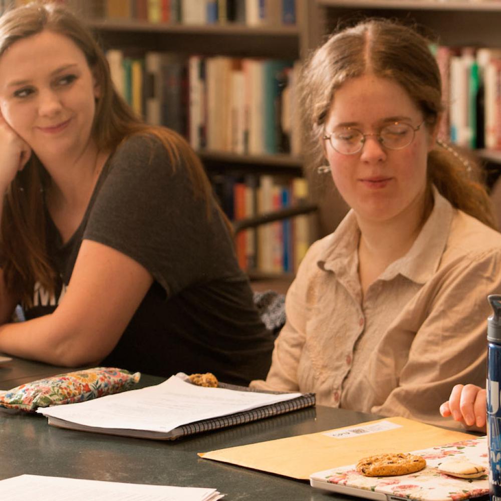 Students gather around a small table in a lively discussion with their professor