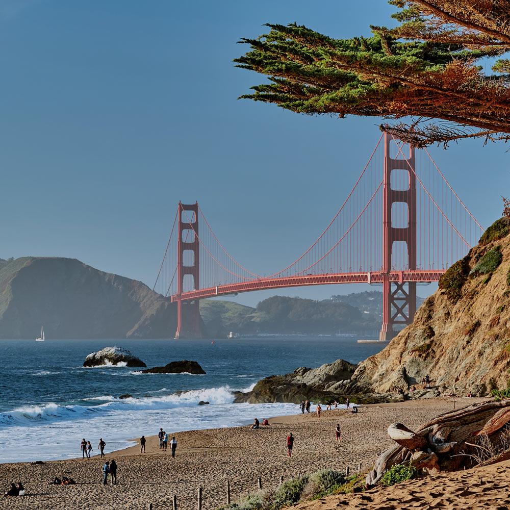 A scene of Baker Beach in San Francisco with the golden gate bridge in the background