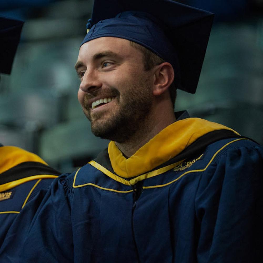 A male student smiles at his commencement ceremony
