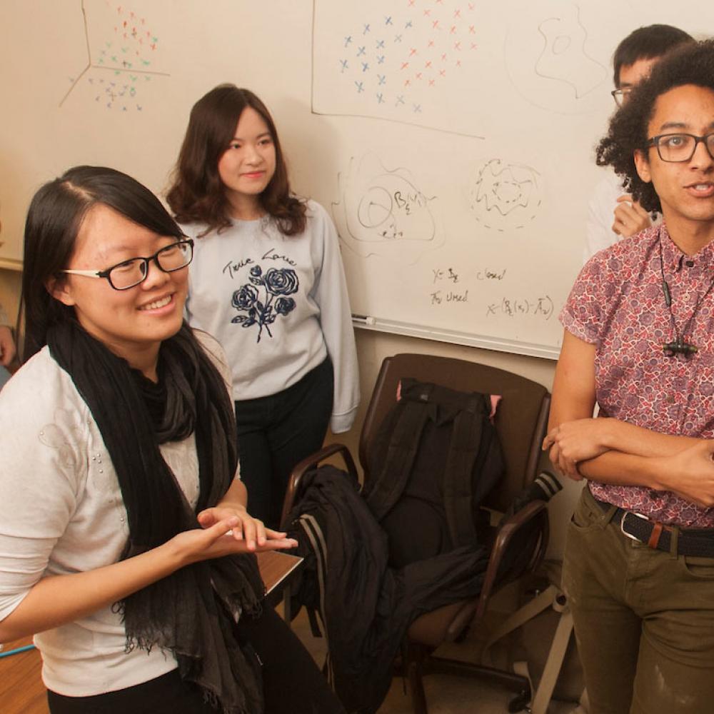 A group of math students considering a complex problem on a blackboard