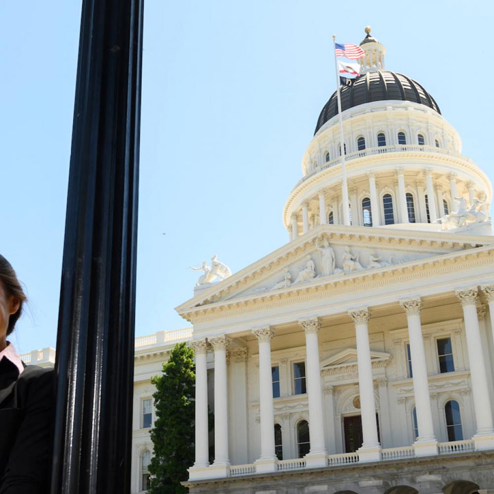 A female student poses with the California State Capitol building in the background