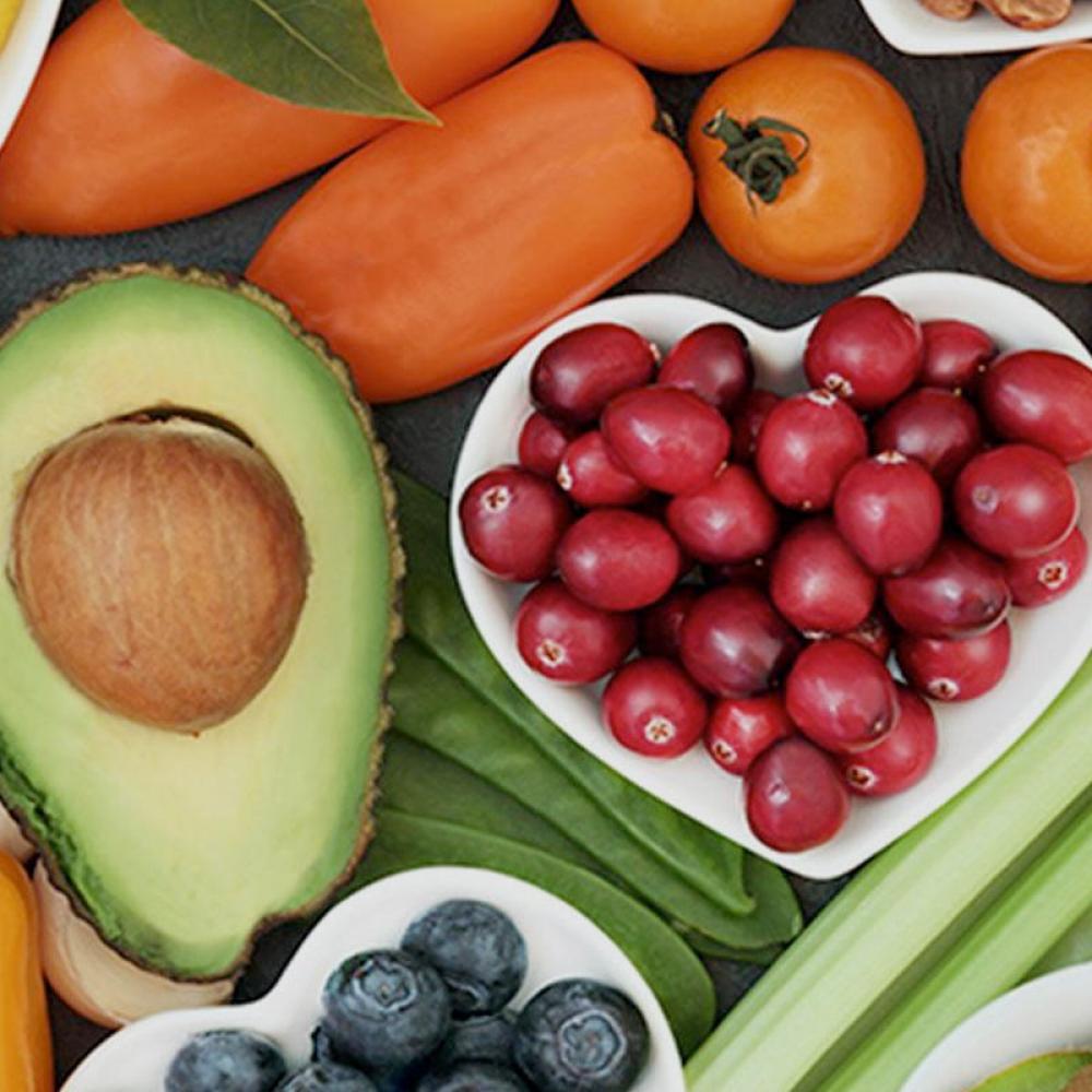 A display of several different superfoods including cherries, avocados, blueberries, peppers and other fruits and vegetables