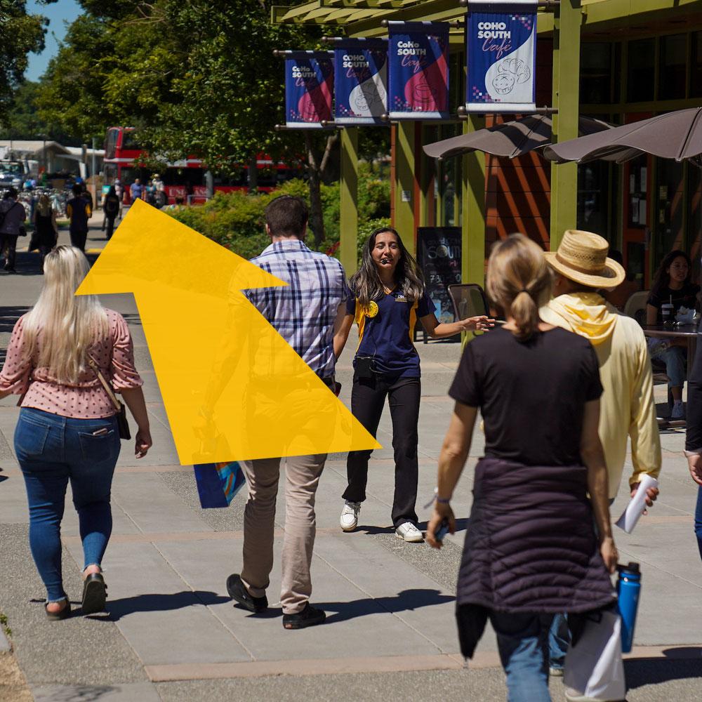 A tour group walks through campus with a digital arrow superimposed over them.