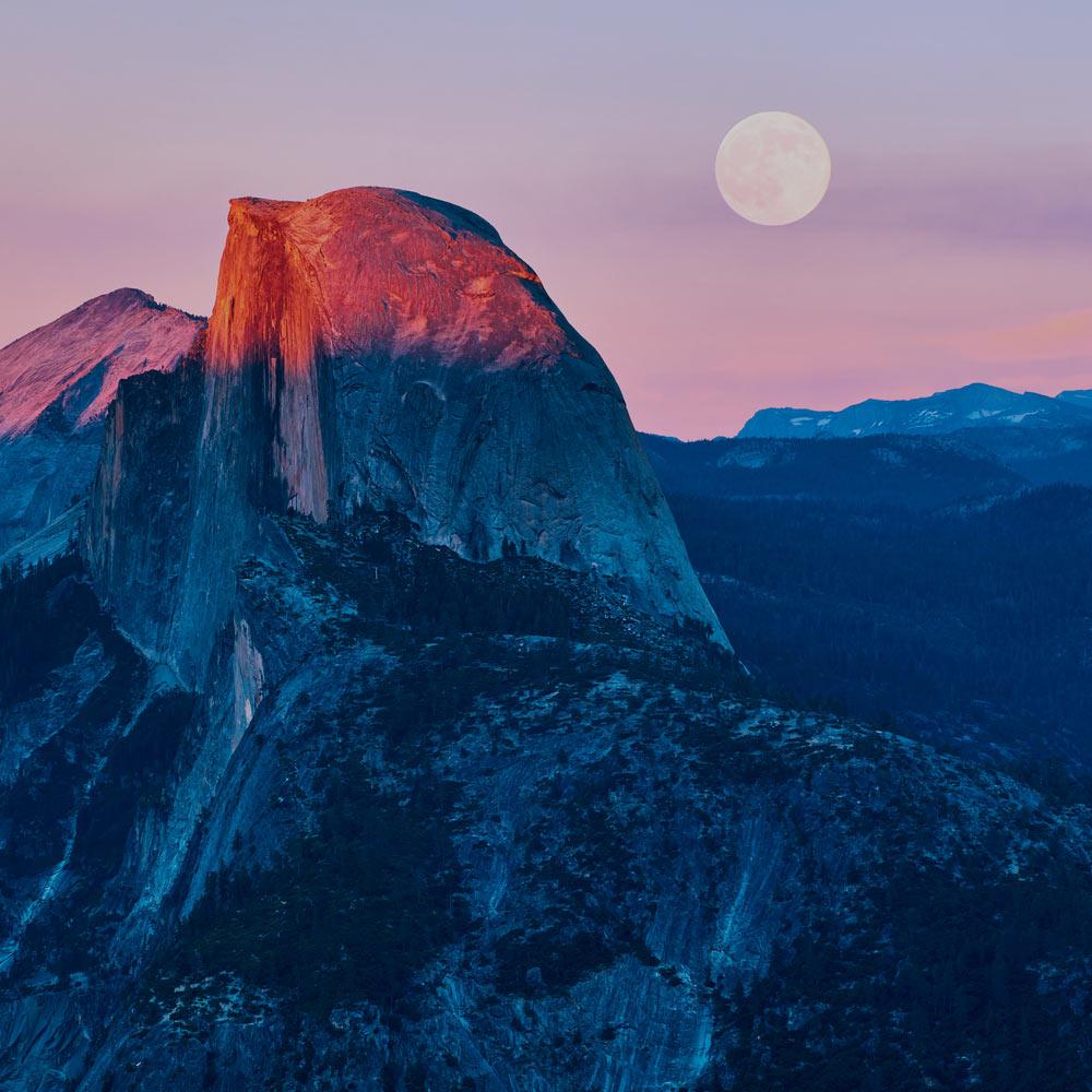 Half Dome gleams in the sunset with a rising moon in the background.
